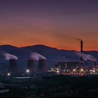 Outdoor image of industrial warehouse with the sunsetting behind mountains in the background