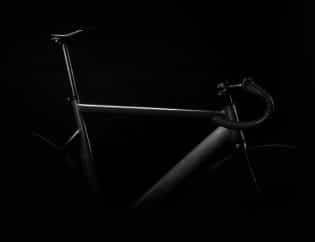 Close up image of the handles on a black stationary bike against a black background