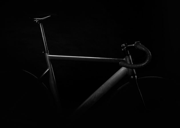 Close up image of the handles on a black stationary bike against a black background