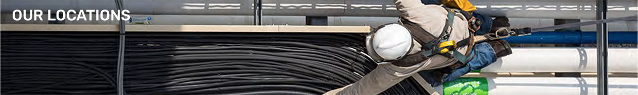 Panoramic overhead image of a man working with wires wearing a white hard hat. Text overlay reads OUR LOCATIONS