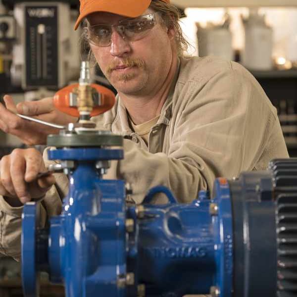 Motor technician wearing an orange hat repairing a small motor.